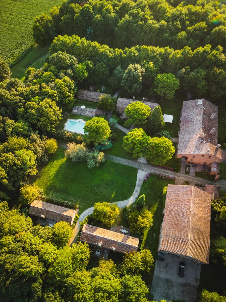 Vista dall'alto della tenuta: casali, piscina e prato immersi nel bosco