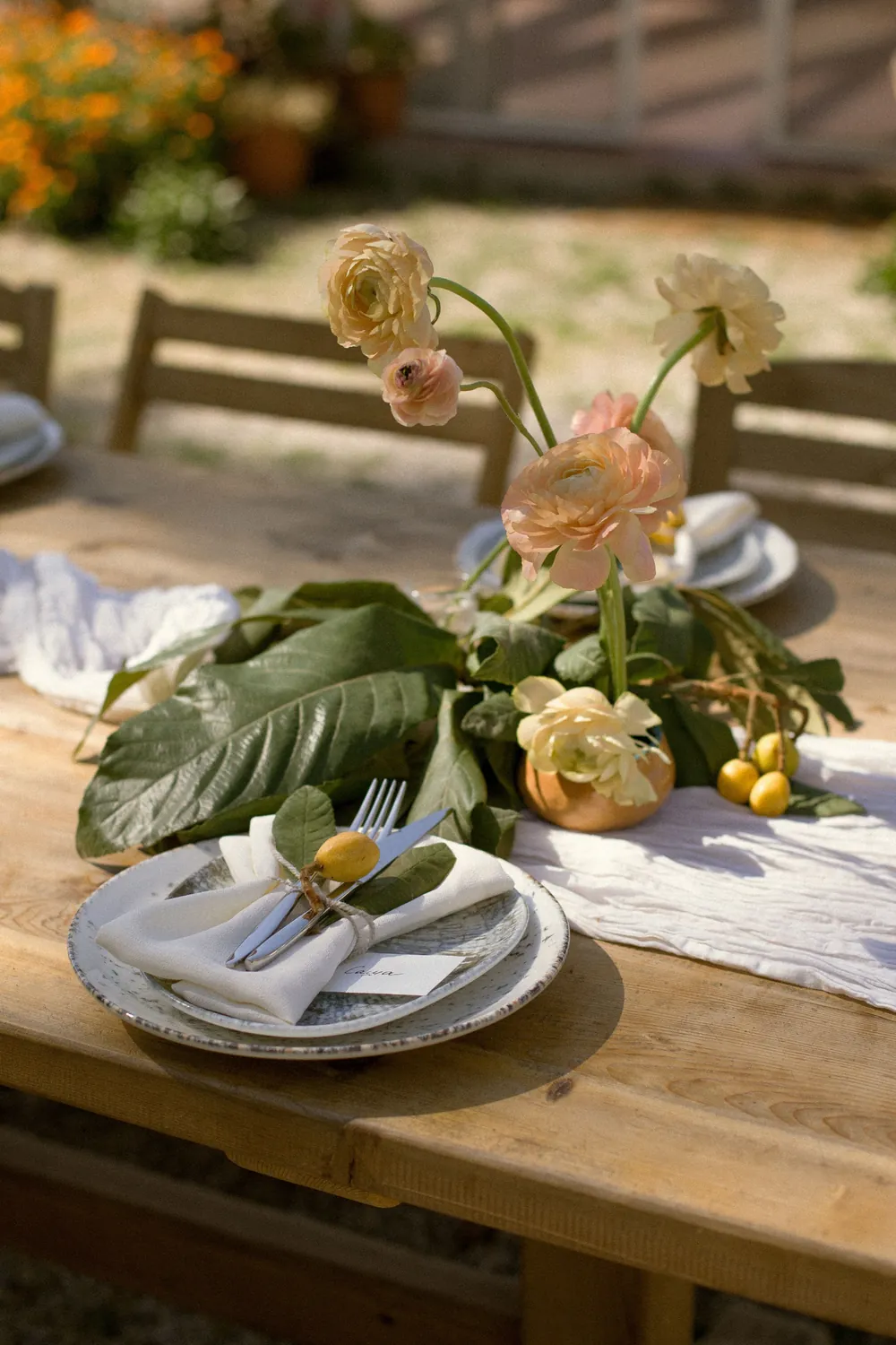 Tavola apparecchiata all'aperto con fiori, piatti in ceramica e tovaglioli di lino